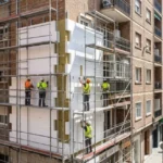 Edificio residencial en proceso de rehabilitación energética con instalación de placas de aislamiento SATE y andamios